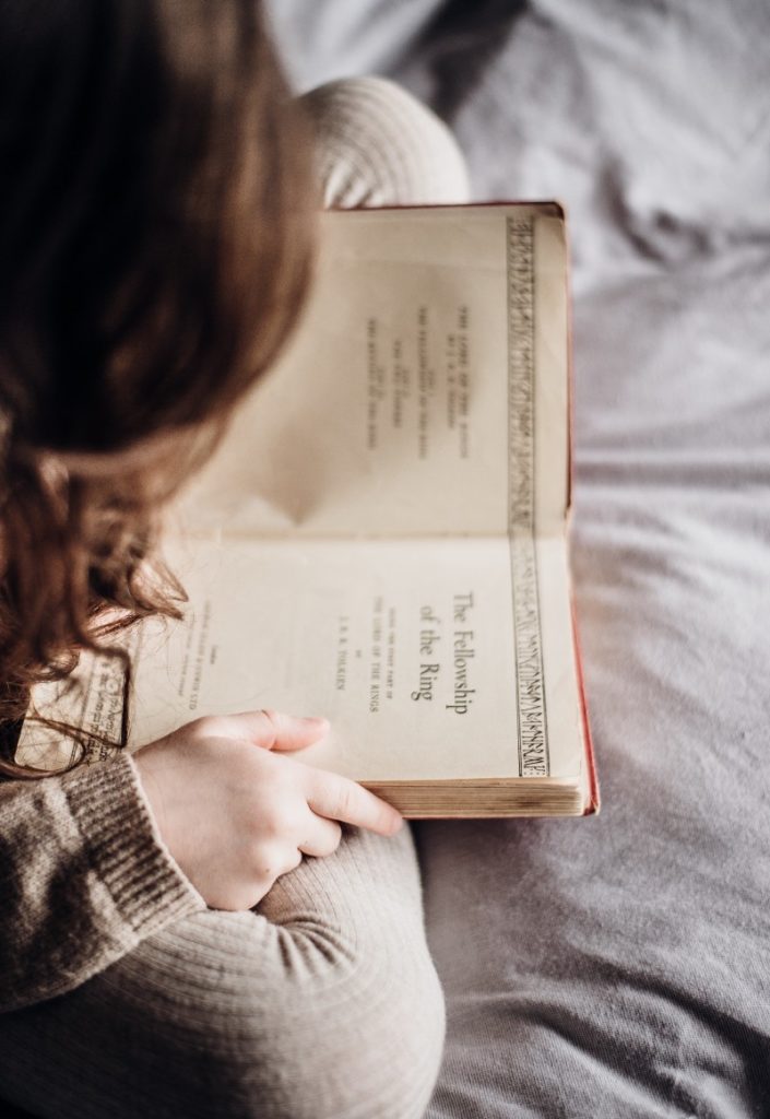 Girl reading Fellowship of the Ring on a bed