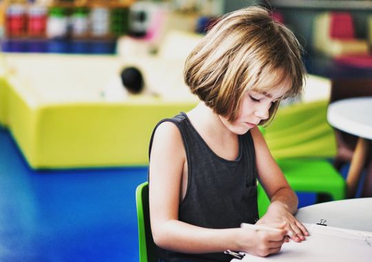 young girl writing at a desk in a notebook